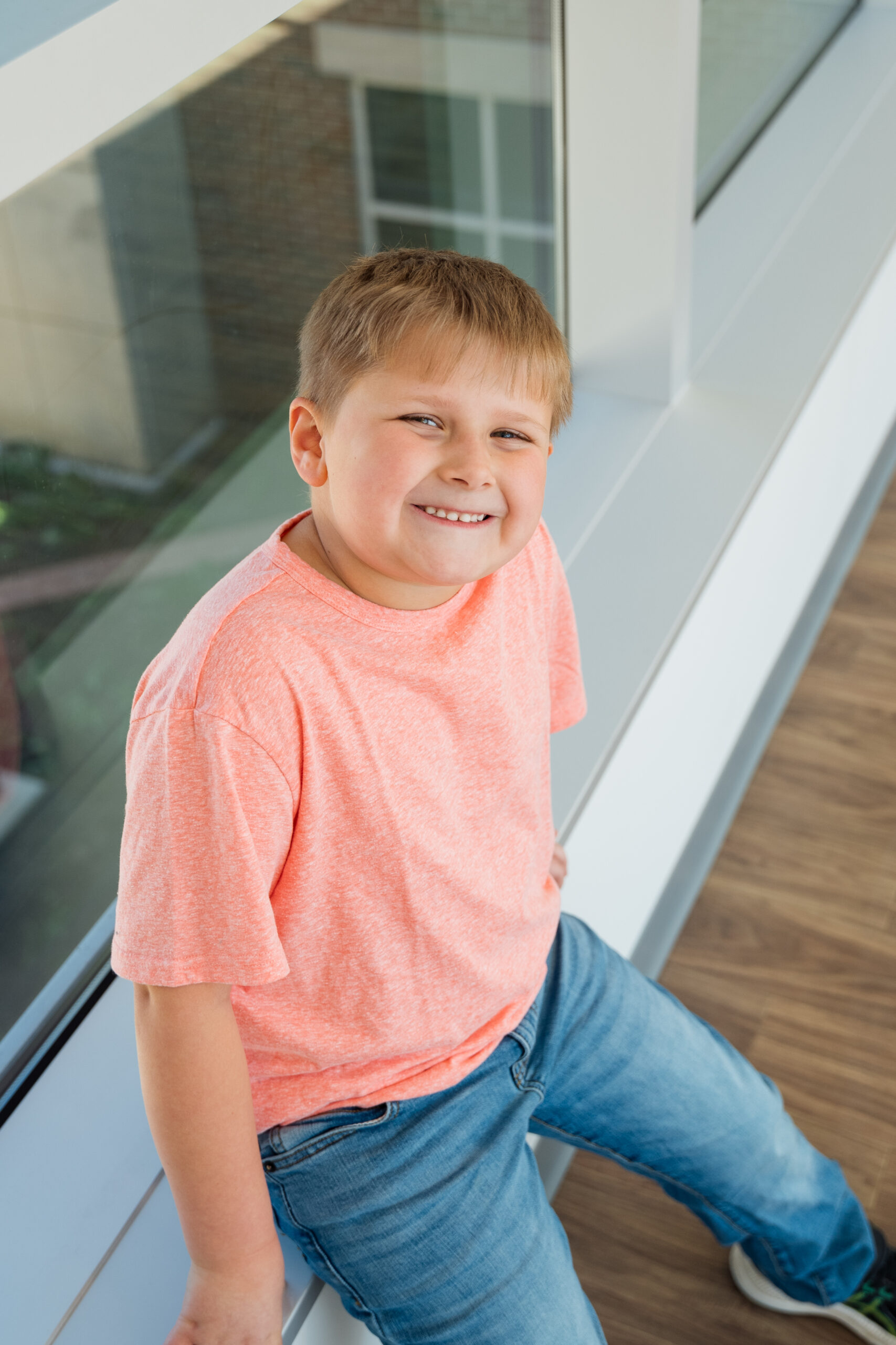 A young boy smiles at the camera while sitting down after his appointment with the psychology department.
