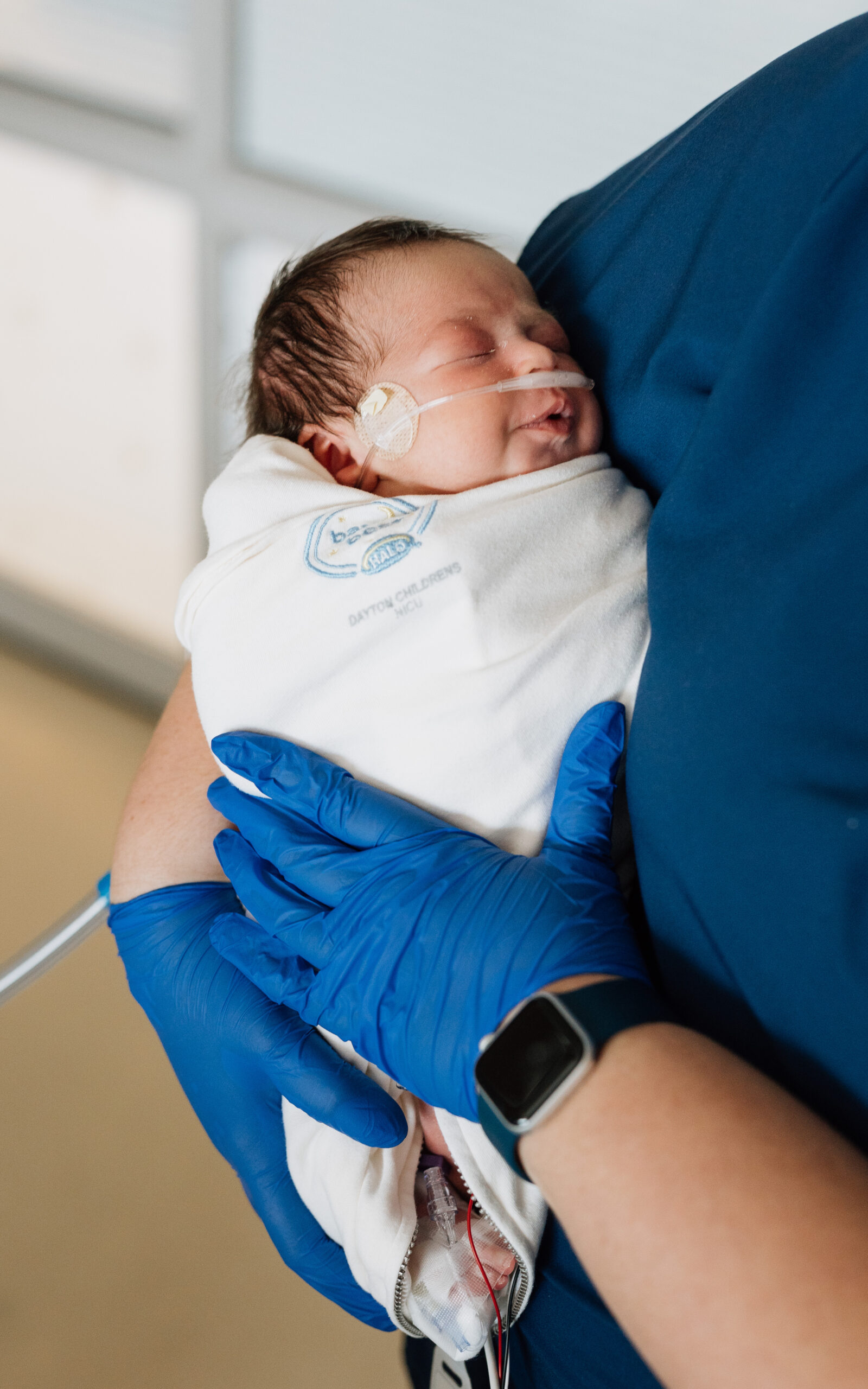 A swaddled baby is being held by one of the staff. 