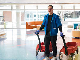 A hospital volunteer delivers meals through the hallway, representing the essential daily support that helps hospital teams focus on patient care.