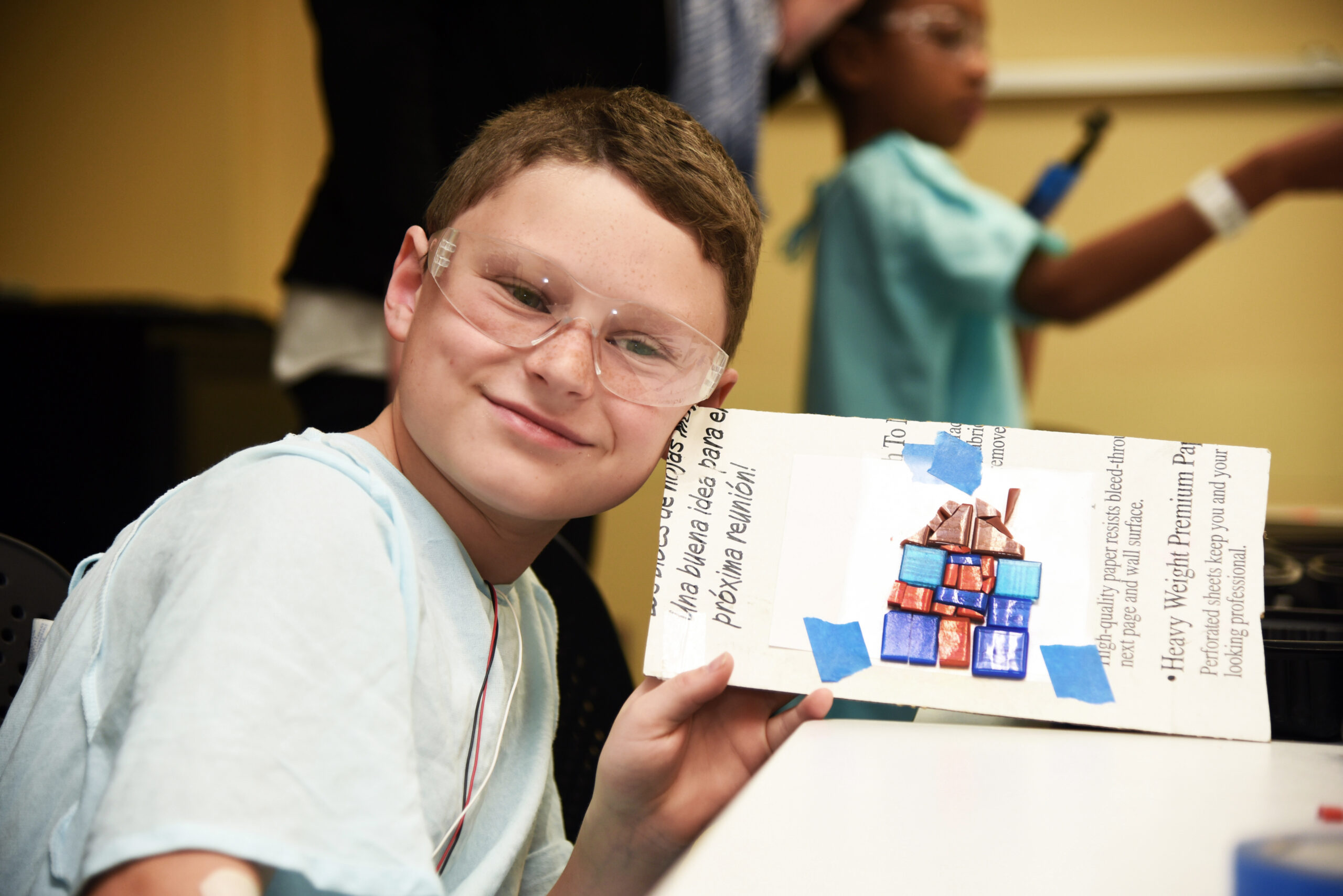 A preteen boy shows off his finished piece of mosaic work that will eventually be a part of the SkyDeck at Dayton Children's.