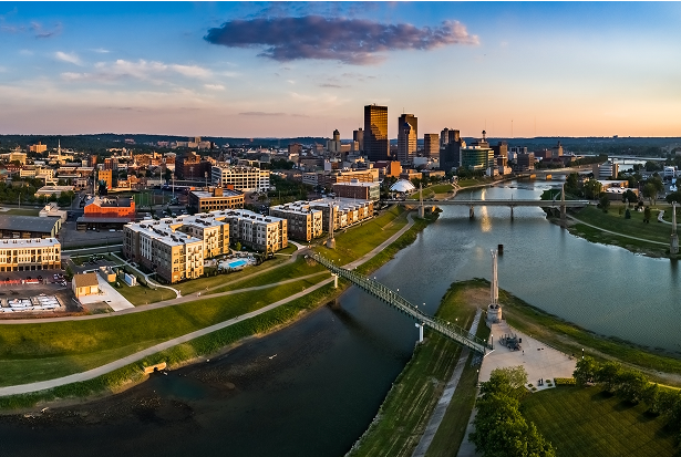 An aerial view of a city skyline with buildings, bridges, and a river at sunset.