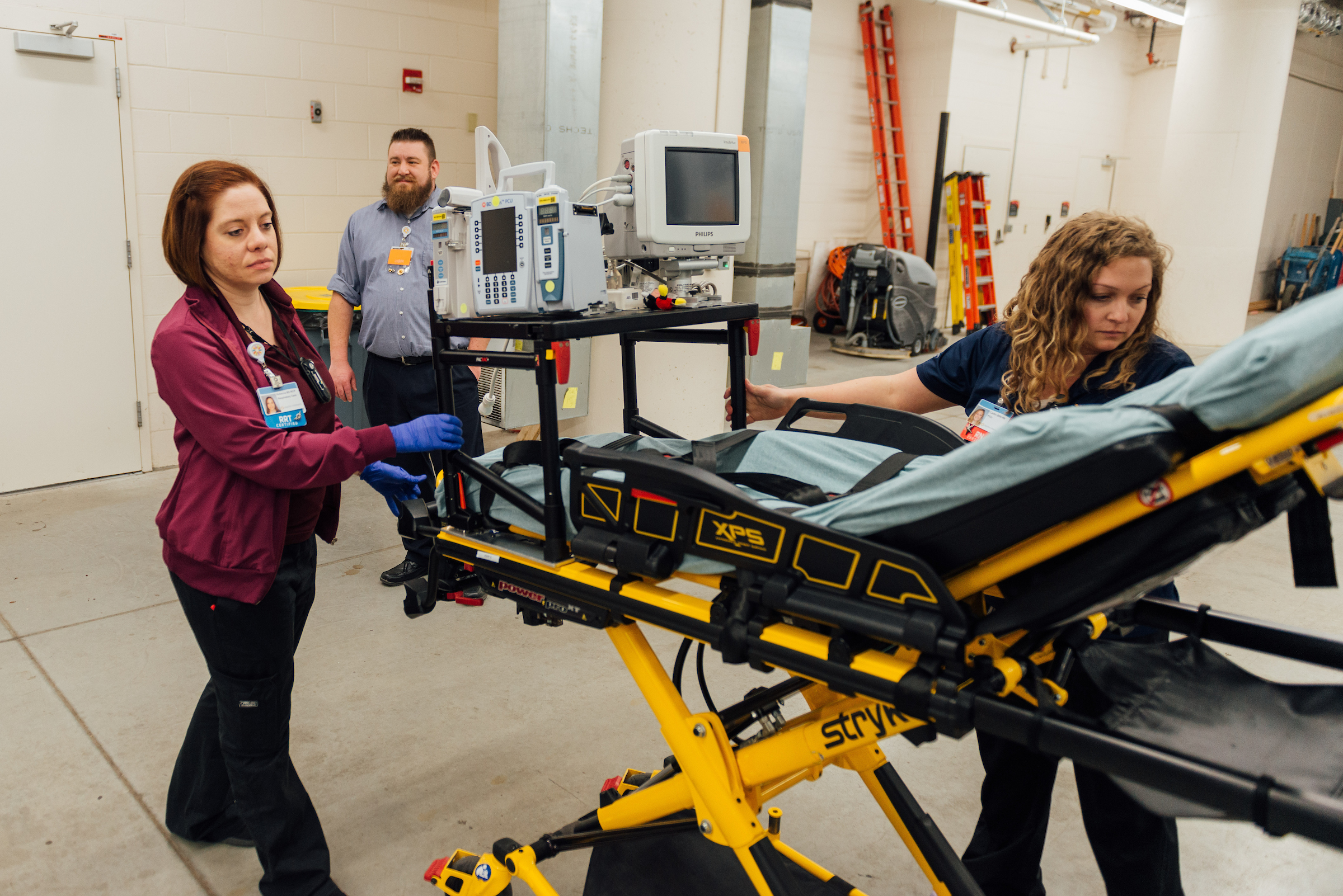 Healthcare professionals continuing education for pediatric care as they learn about intensive care transport while loading a cot into an ambulance.