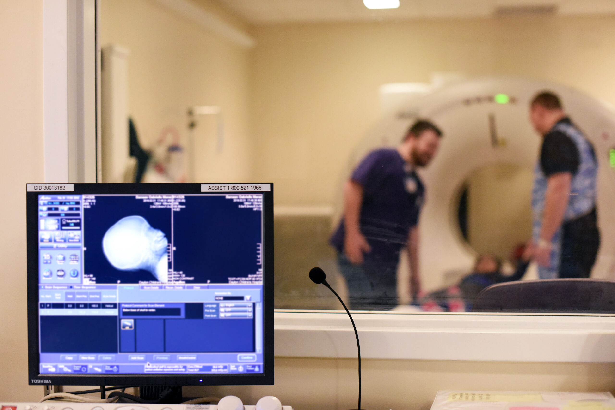 A computer screen displays the results of a Dayton Children’s patient’s MRI, with the MRI machine and two techs in the background.