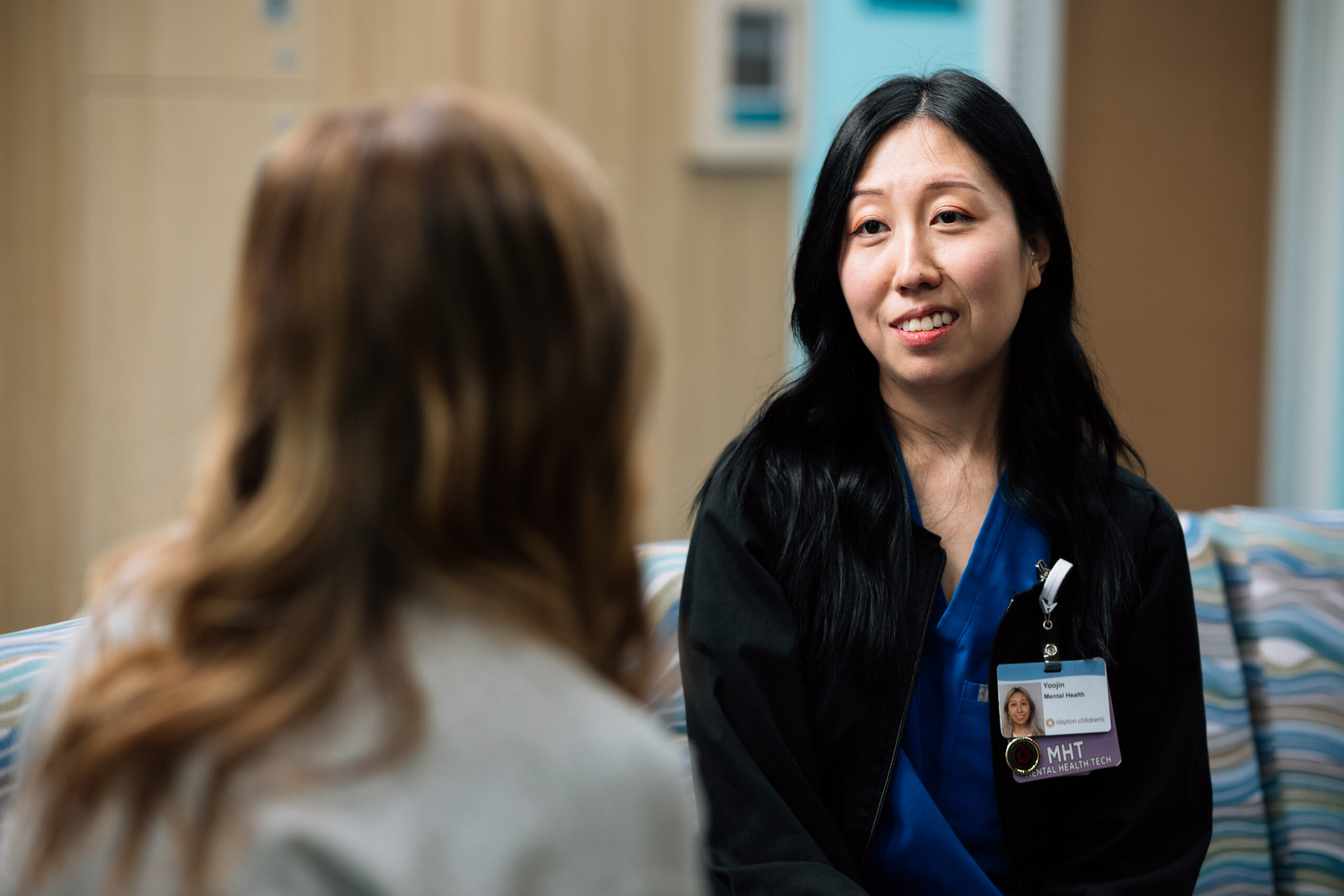 A female mental health tech listens to a patient talk about how they’re coping and offers understanding and comfort.
