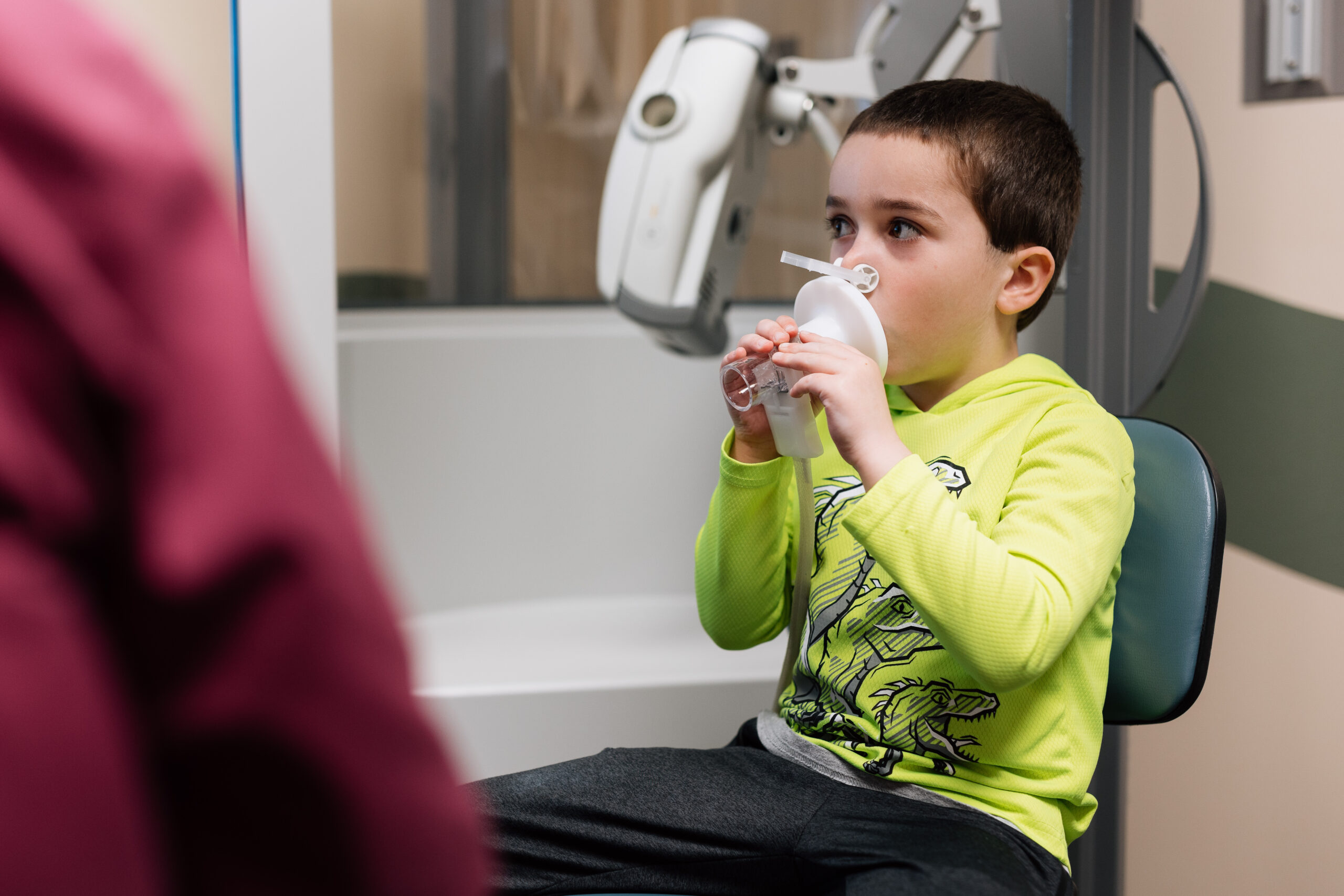 A little boy sits with a respiratory therapist while getting a breathing treatment . 