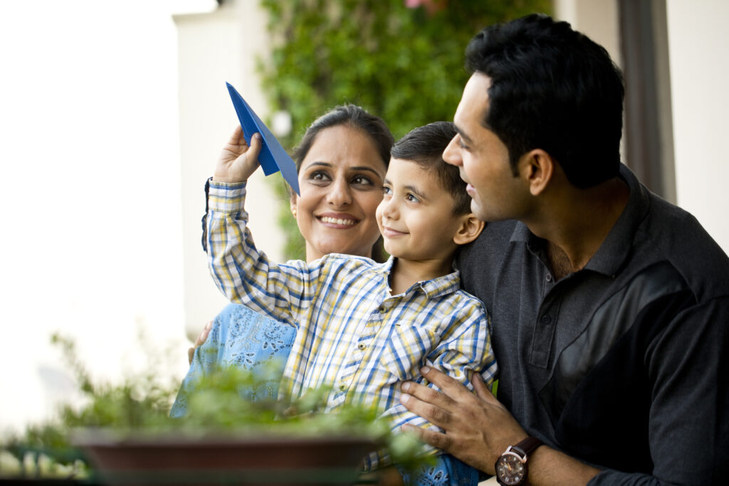 Happy parents with son throwing paper airplane in air
