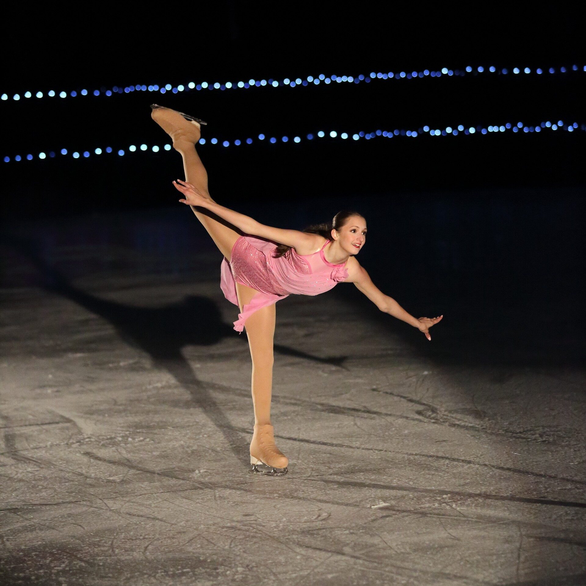 Young female ice skater competes in the spotlight