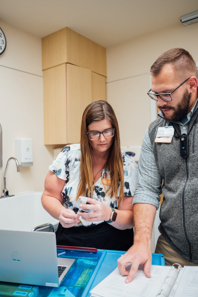 Two pharmacists prepare correct dosage of medicine.