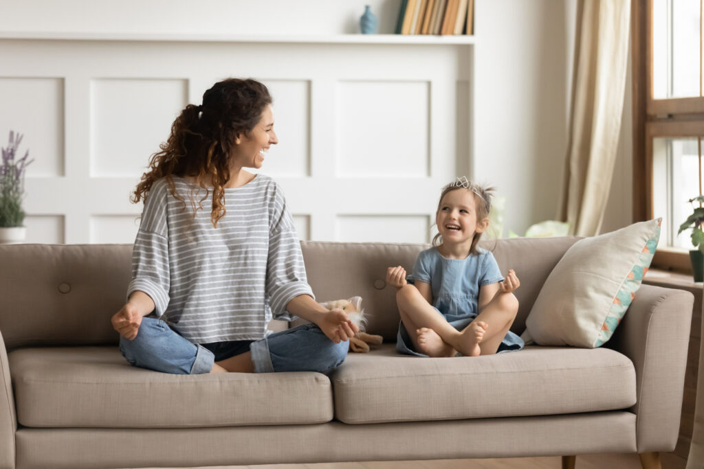 Mother and daughter relax with meditation on the couch