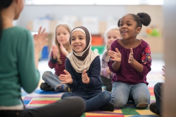 young girls smiling and sitting next to each other in classroom 