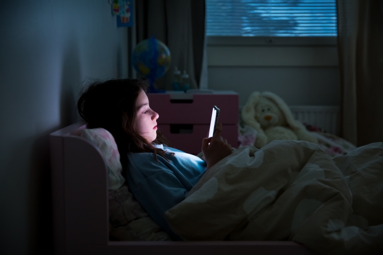 child playing on cell phone while in bed