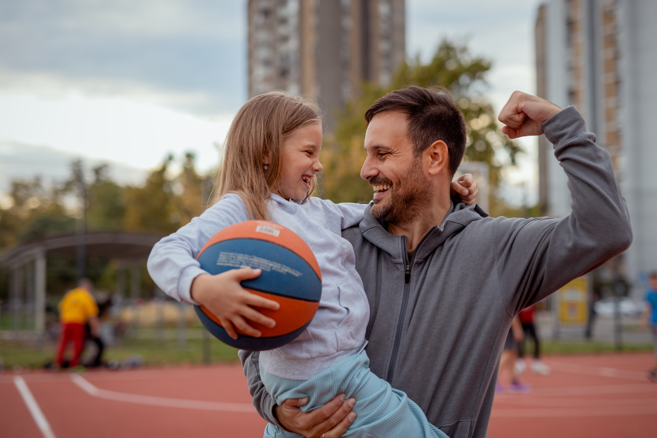 Father and daughter play together on basketball court