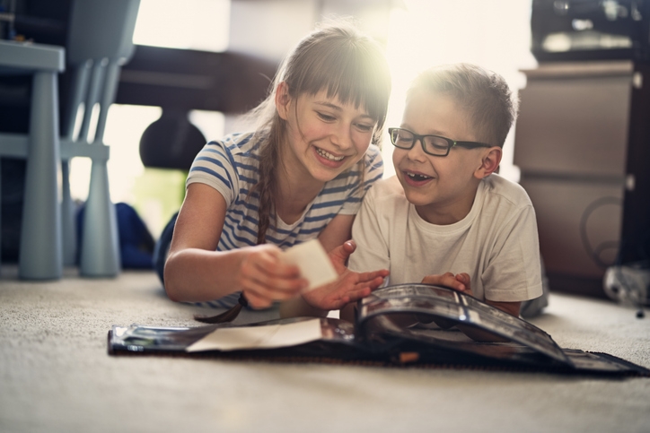 young siblings look in a photo album with fond memories