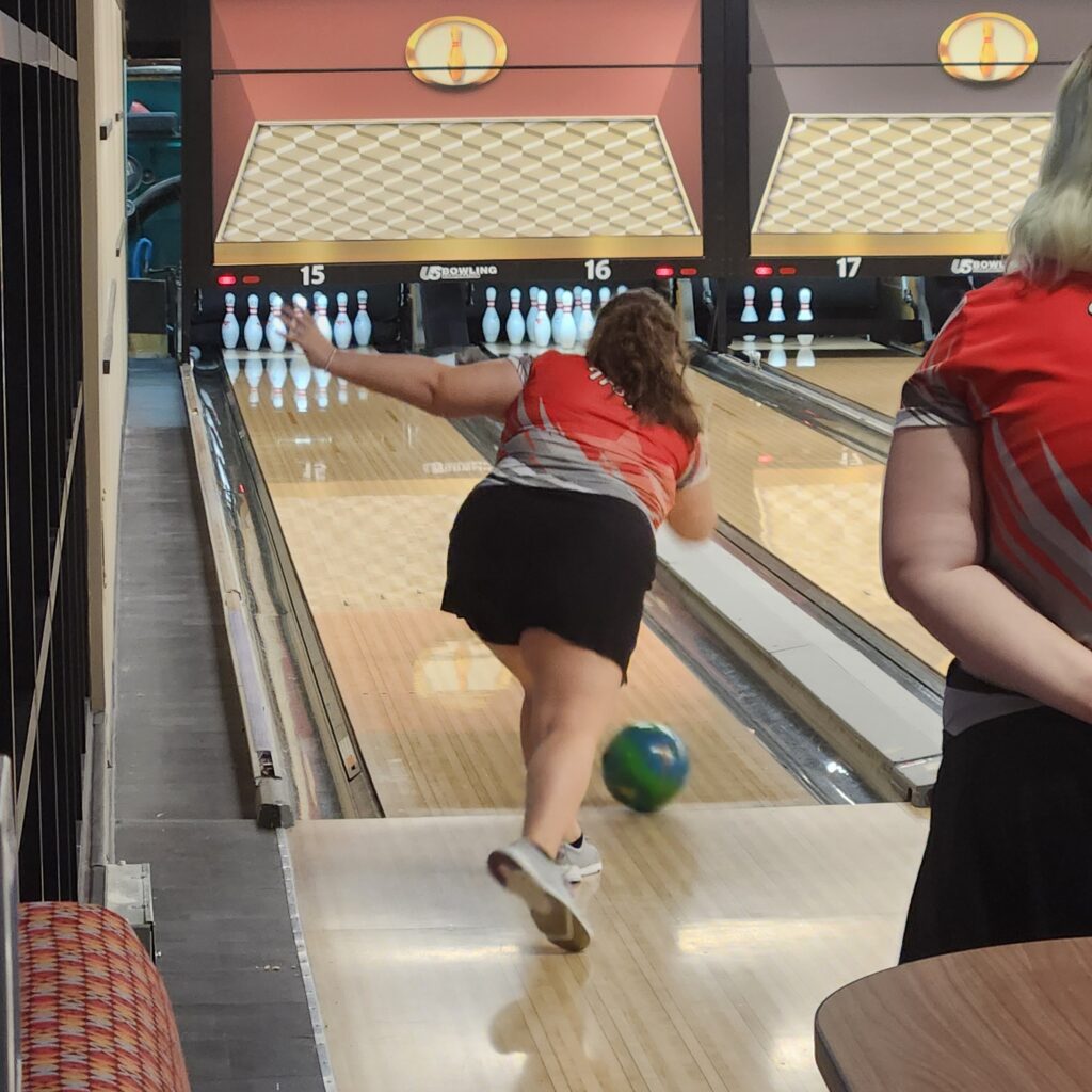 Female bowler rolls ball down the lane