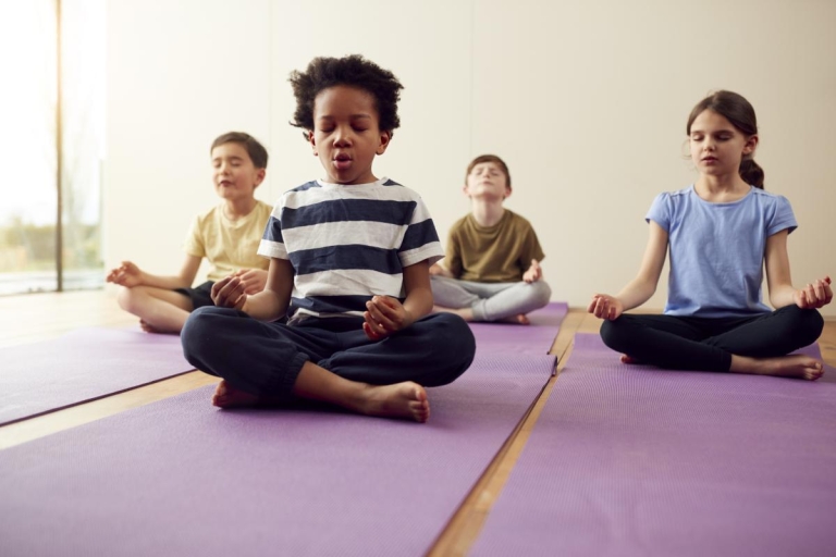 group of children meditate on yoga mats