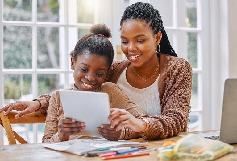 mother and daughter sit at kitchen table and fill out kindness journal activity