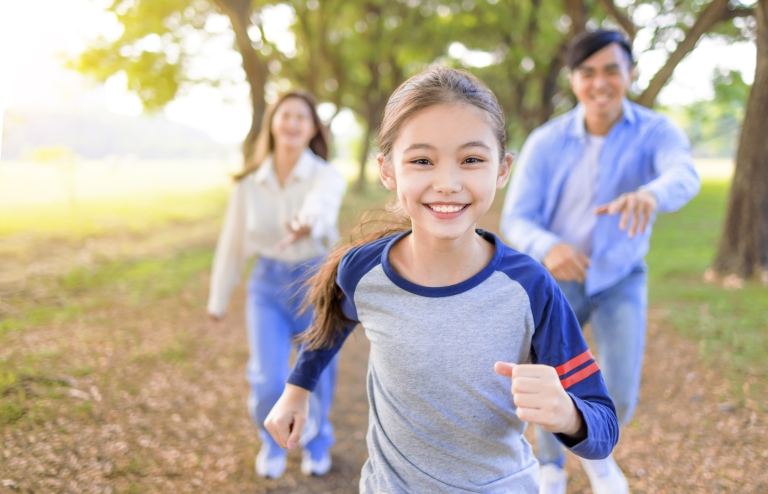 young girl runs on nature trail with family
