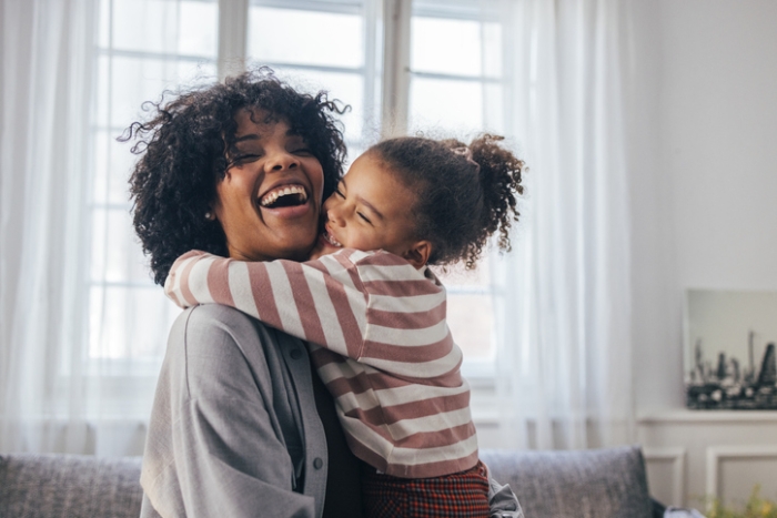 young girl hugs mom while smiling