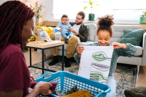young girl helps out her parents by putting away laundry