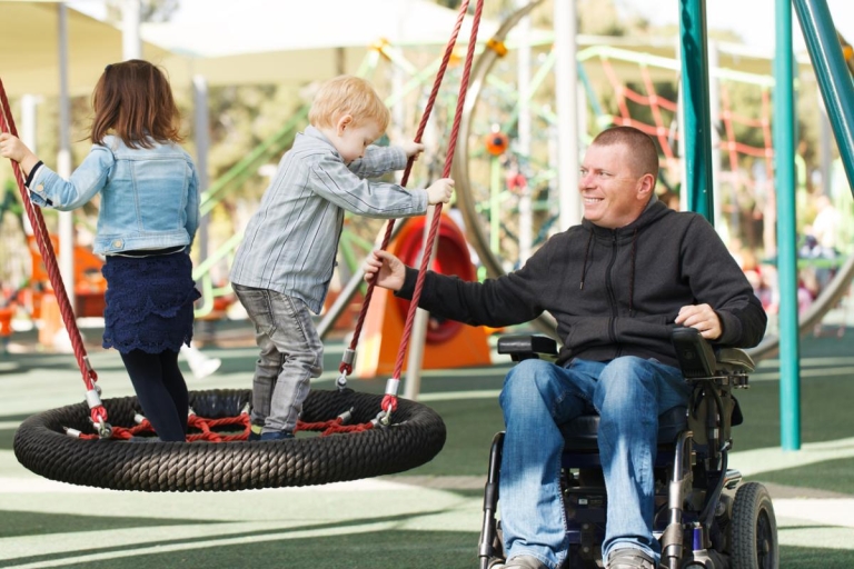 Father plays with his young children at playground