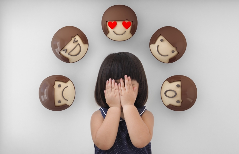 young girl experiences emotions with emojis surrounding her