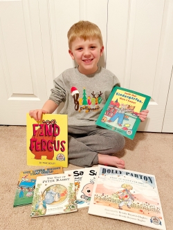 child poses with new books he got from the Imagination Library