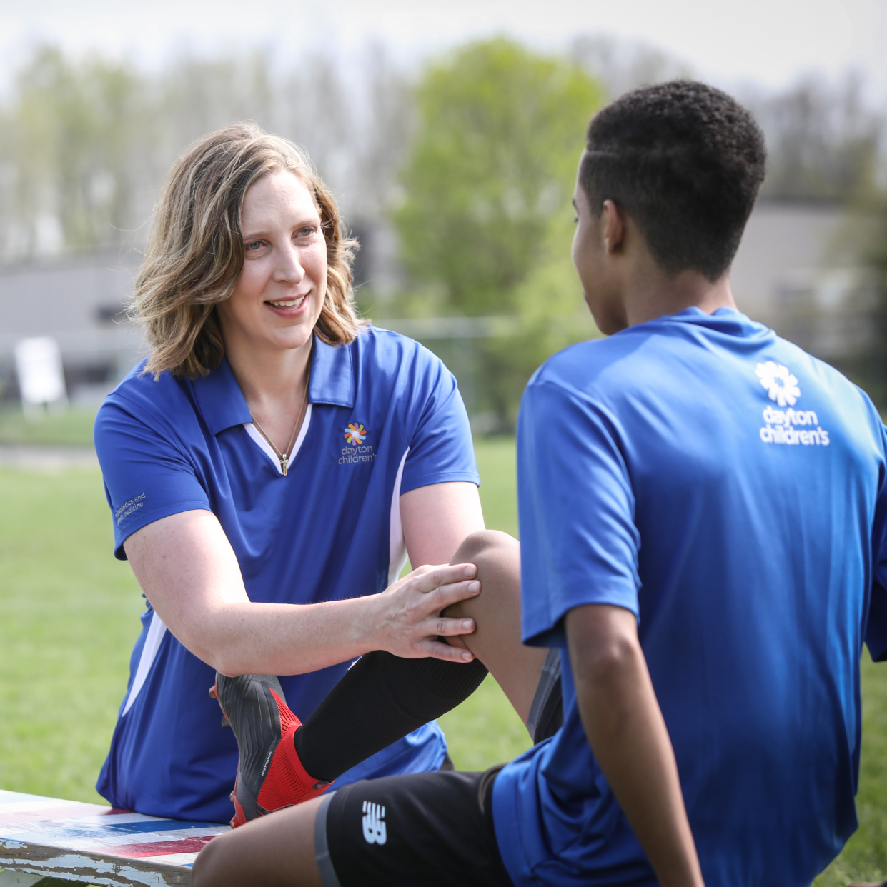 sports trainer checks on player after leaving the field