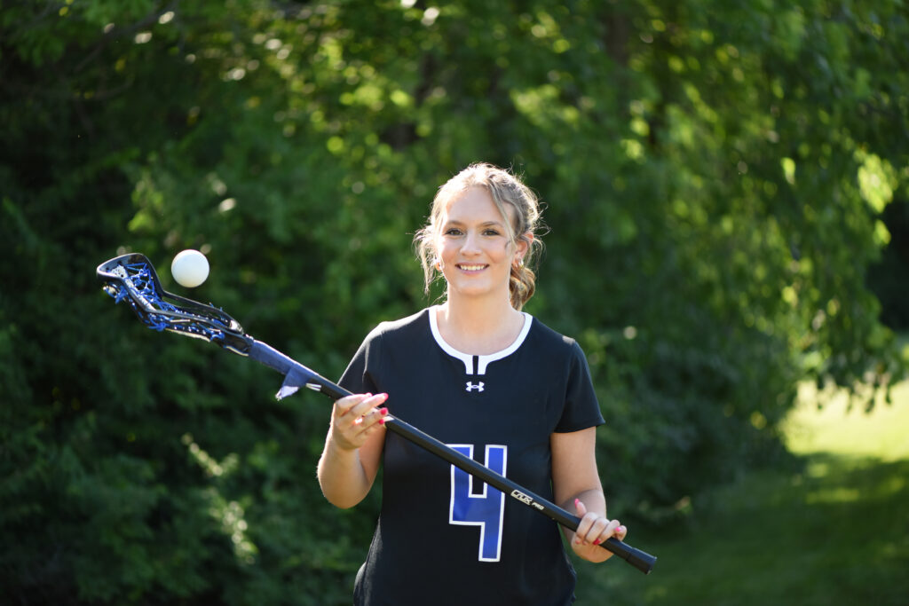 Lacrosse player poses for photo with equipment