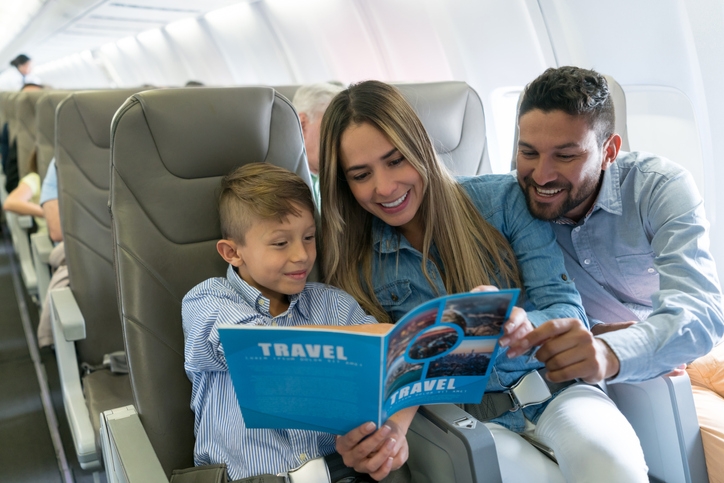 family looks at travel magazine while on an airplane