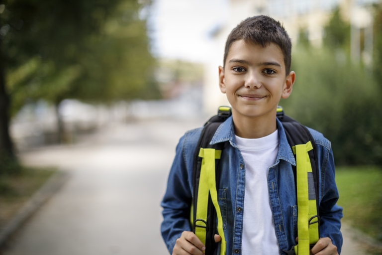 child poses with a backpack on the first day of school