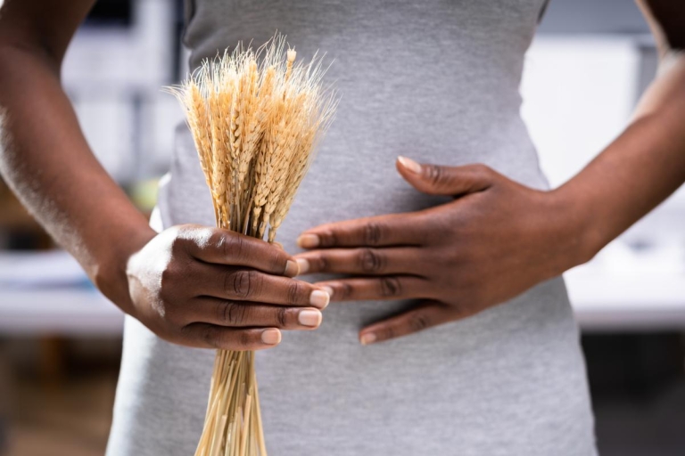 Chef holding wheat while holding stomach, signaling a gluten allergy