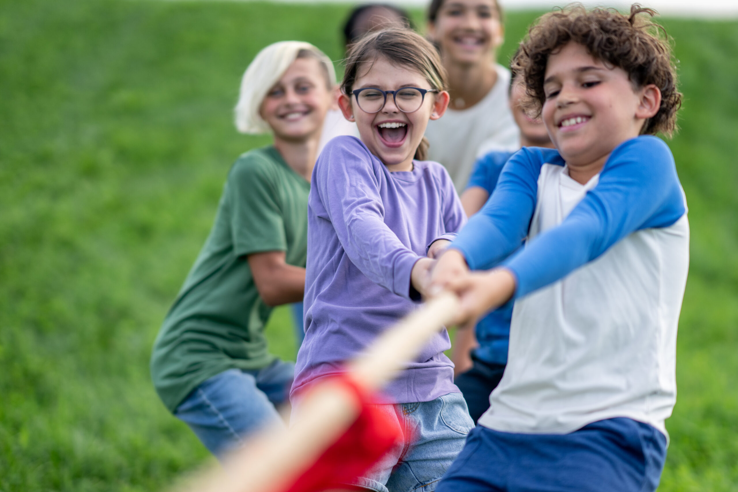 a group of kids at camp play tug of war