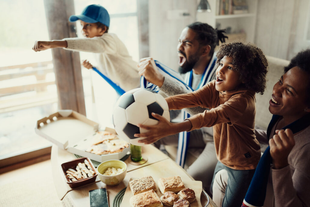 Family cheering on a soccer team at the FIFA World Cup together in their home.