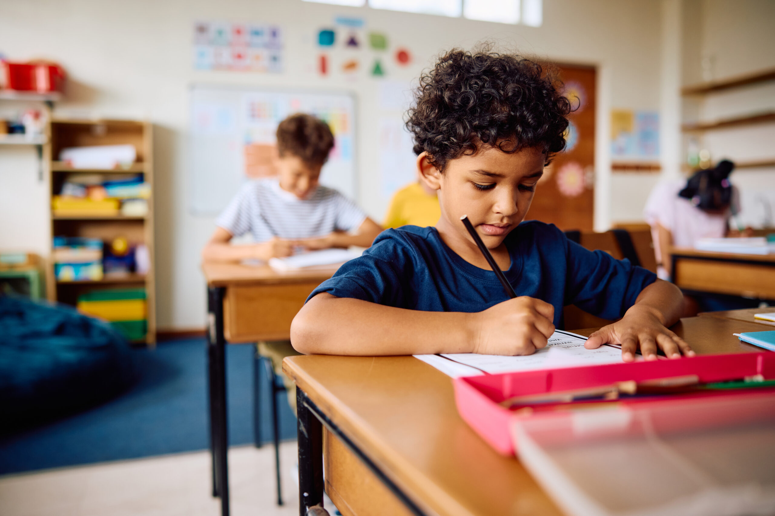 a young boy sits at a desk at school