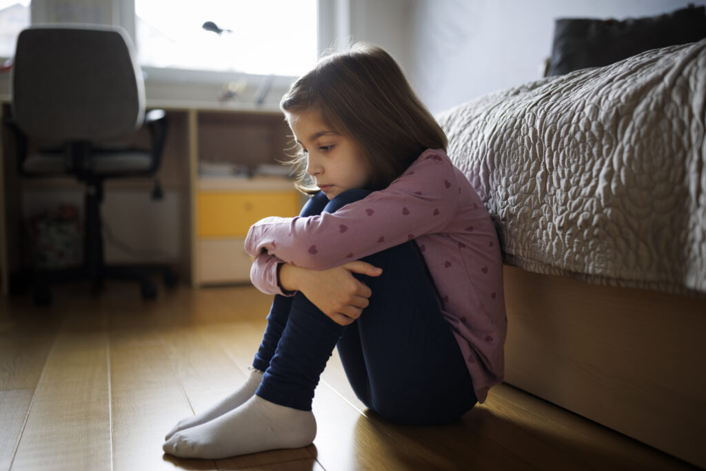 little girl sits in her room with anxiety