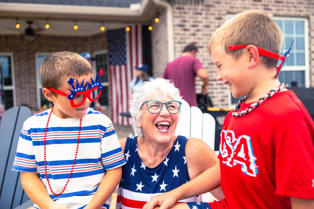 Two young boys smiling and laughing with grandma while celebrating America's 250th birthday.