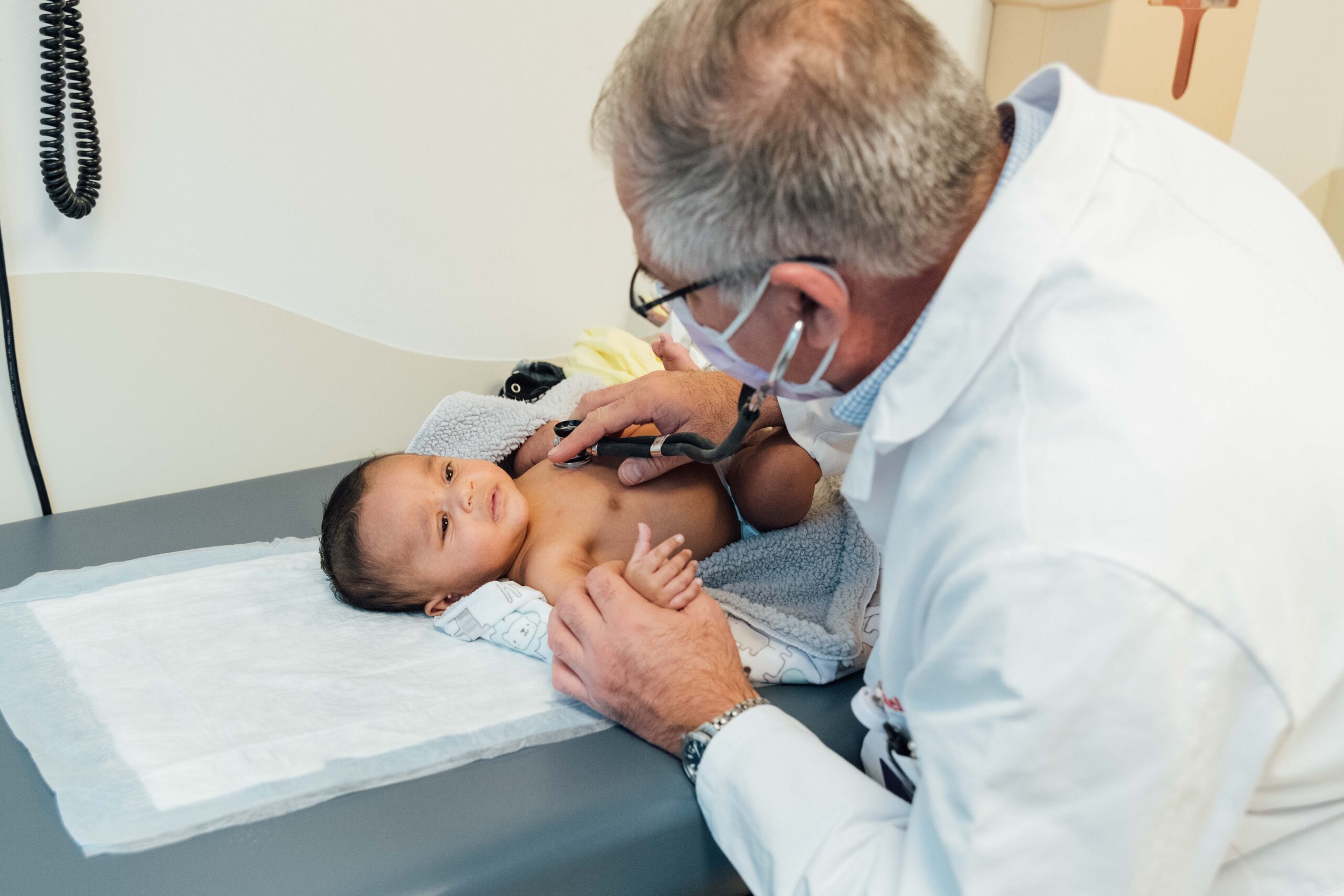 A pediatric cardiology doctor examines an infant patient for a heart condition.