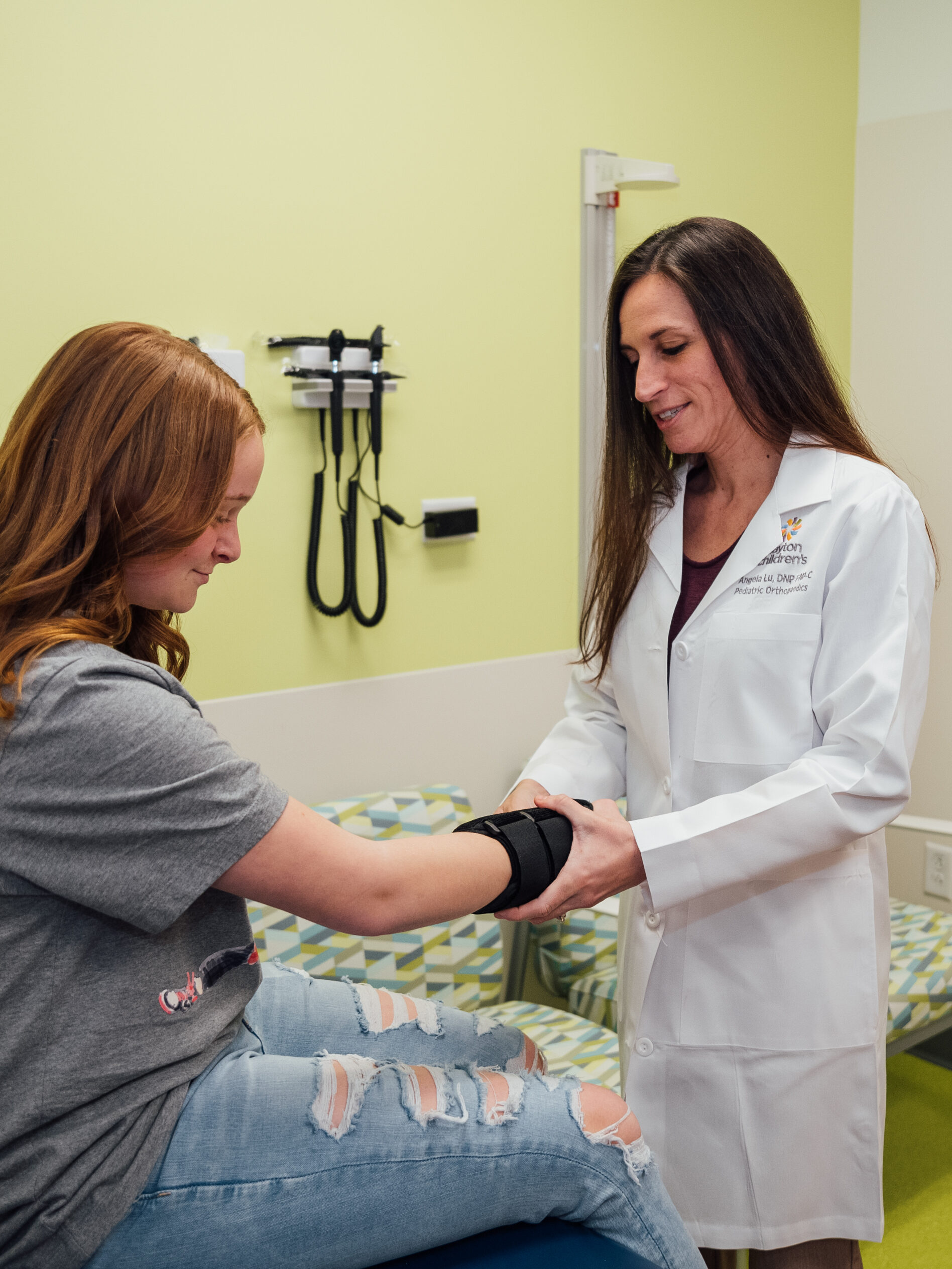 Teenage girl holding out wrist to Dr. Angela Via at pediatric orthopedic appointment