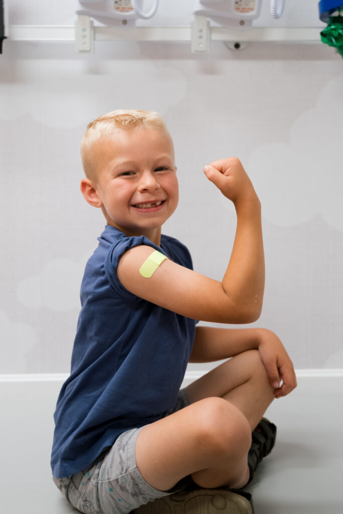 a young boy flexes and smiles after getting his flu shot